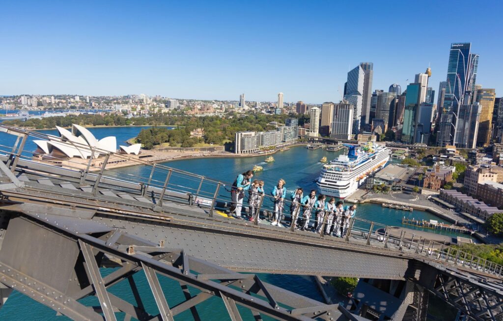 A group of people climbing the Sydney Harbour Bridge, one of the most popular things to do in Australia, with a view of the Park Hyatt Sydney in the foreground.