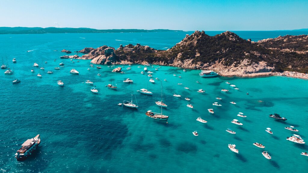 Boats in turquoise water along the Sardinia coastline, a top Italy travel destination.