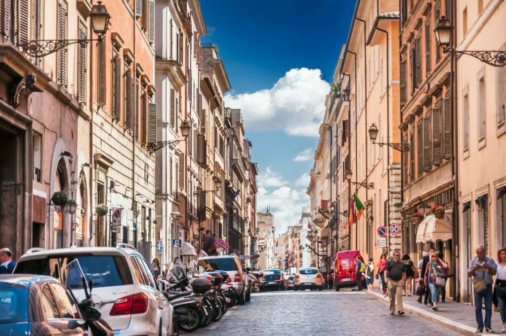 Historic street in Rome with cars, pedestrians, and limited driving space in the city center.