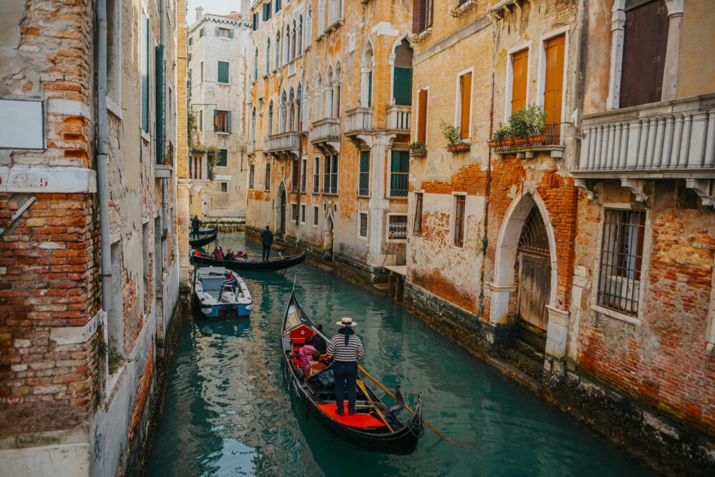 Travelers riding in a gondola along a canal in Venice, Italy